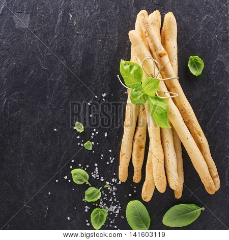 Fresh homemade crispy bread sticks with thyme and sea salt on a black background with fresh herbs. selective focus