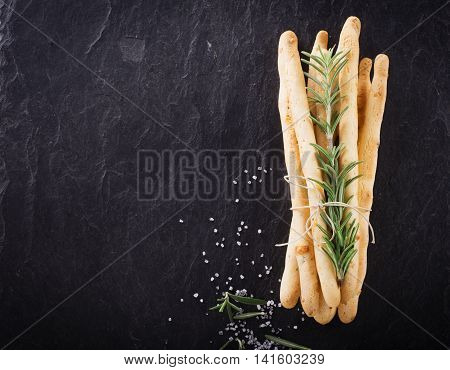 Fresh homemade crispy bread sticks with thyme and sea salt on a black background with fresh herbs. selective focus
