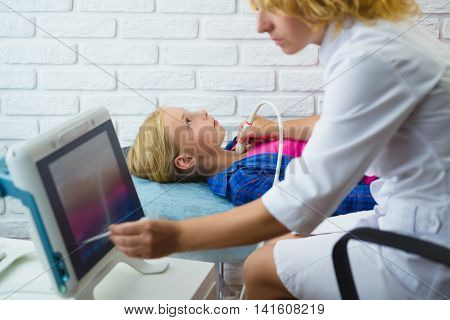 Female doctor examines girl patient with ultrasound in medical center.