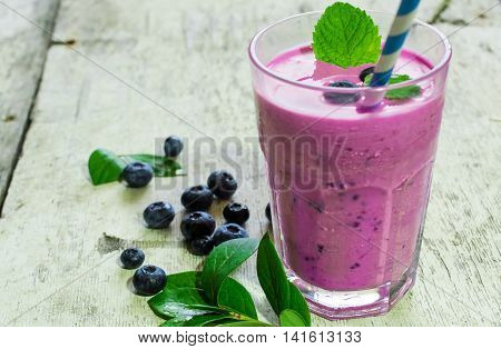 smoothie yogurt with blueberries and fresh mint on rustic wooden background. shallow depth of field