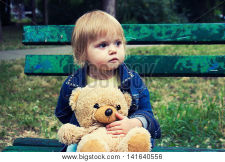 Toddler sitting on the bench in the park