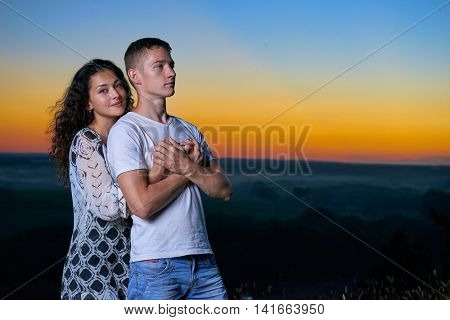 romantic couple portrait at sunset on outdoor, beautiful landscape and bright yellow sky, love tenderness concept, young adult people