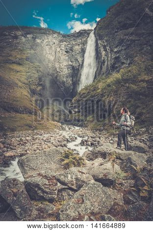 Woman hiker with backpack standing near Vettisfossen waterfall. Norway.