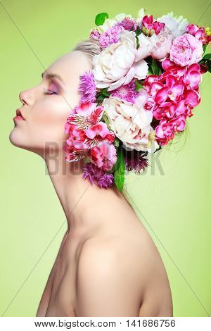 Beautiful girl, isolated on a light - green background with varicoloured flowers in hairs, emotions, cosmetics