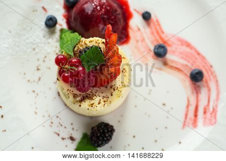 Top view of small cake. Dessert with currant and mint. Cheesecake and fruit ice cream. Delicious and healthy dish.