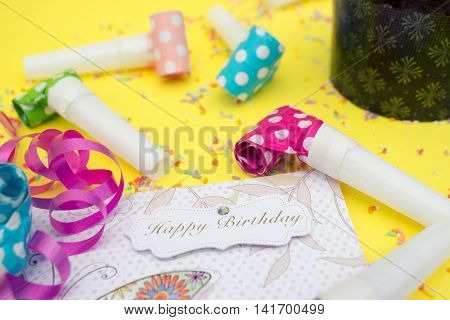 Party horns (whistles) and happy birthday card on yellow background