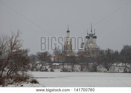 Orthodox temple on the banks of a frozen river winter