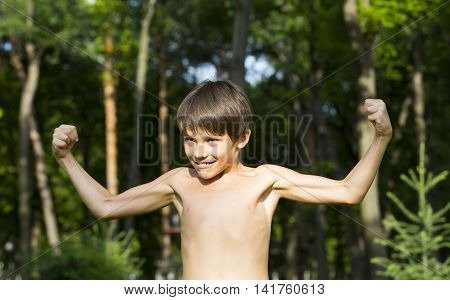 portrait of a boy in nature which shows his muscles