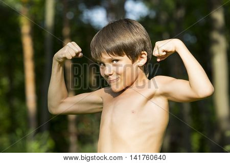 portrait of a boy in nature which shows his muscles