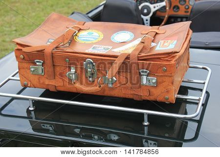 Vintage leather suitcase on a sports car