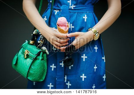 girl with green bag and glasses holding a pink ice cream cone