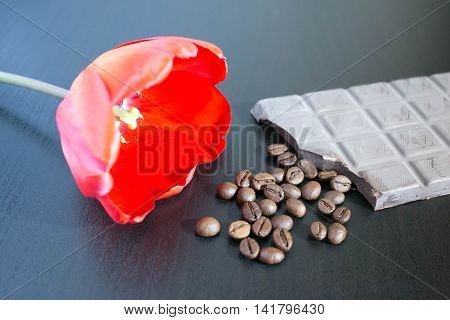 Bunch of orange roses with dark chocolate and coffee beans on old wooden table.