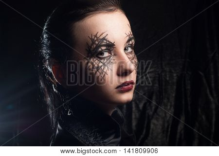 Young beautiful girl with make-up for Halloween body art on a woman's face mystical makeup