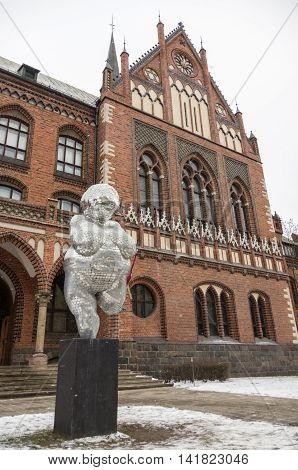 Riga, Latvia - January 1, 2016: The brick gothic building of Academy of Art in Riga with woman statue from mirror pieces.