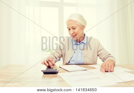 business, savings, annuity insurance, age and people concept - senior woman with papers or bills and calculator writing at home