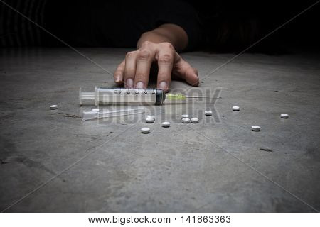 Close-up on the floor of the syringe with the drug. In the background a young drug addict