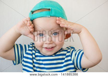 A cute white baby boy with big blue eyes is looking surprisingly into the camera