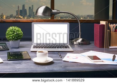 Creative hipster desktop with blank white laptop computer tablet smartphone coffee cup table lamp calculator plant and other items on window with city view background. Mock up