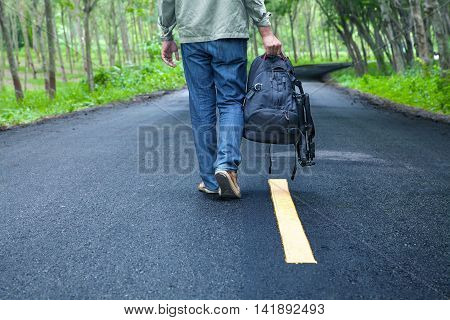 Hitchhiking Tourism Concept. Travel Hitchhiker Man With Backpack Walking On The Road Passes Through