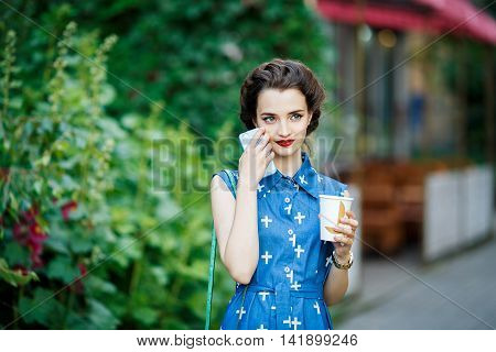 Vintage woman wearing a blue dress holding a cup coffee