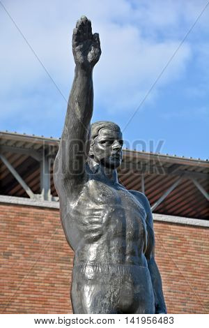 AMSTERDAM NETHERLANDS 02 10 2015: Sculpture by Gra Rueb Official Olympic Salute Stopped Being Popularly Used After WWII Due to Strongly Resembling the Heil Hitler Salute. In front the olympic stadium