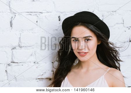 Girl portrait of a beautiful young brunette in a black hat