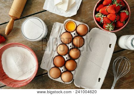 Top View Raw Ingredients For Cooking Strawberry Pie Or Cake On Wooden Table (eggs, Flour, Milk, Suga