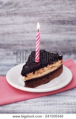 Chocolate Cake With Candle. Piece Of Desert Birthday Cake Isoalted On Gray Woden Table