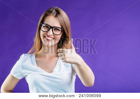 Portrait Of Pretty Blonde Woman Dressed In White T-shirt And Eyeglasses Shows Thumbup Sign, Isolated
