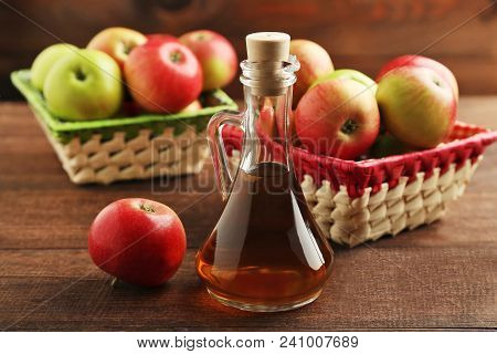 Apple Vinegar In Glass Bottle On Brown Wooden Table