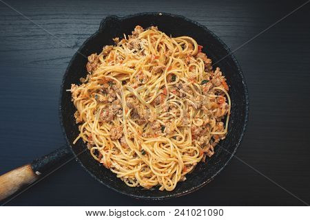 Appetizing Spaghetti In An Old Frying Pan With Bolognese Sauce On A Dark Background Close Up