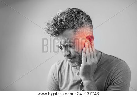 Male Having Ear Pain Touching His Painful Head Isolated On Gray Background