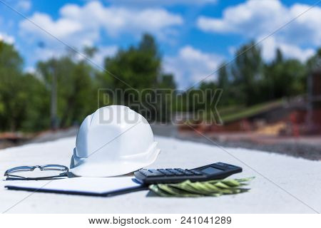 Helmet With Glasses And A Clipboard And Calculator And Money. Outdoor Construction