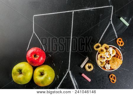 Healthy And Unhealthy Snack Concept With Crackers, Chips And Apples On Black Chalkboard