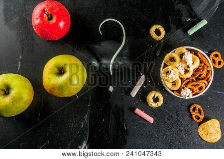 Healthy And Unhealthy Snack Concept With Crackers, Chips And Apples On Black Chalkboard