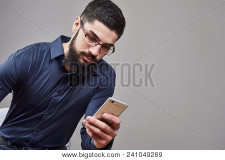 Happy Man In Glasses Typing Sms On Gray Background.