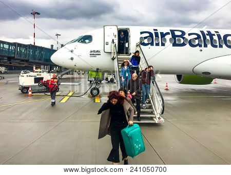Riga, Latvia - May 5, 2018: Passengers get off the Airbaltic plane arrived in Riga on a rainy day.