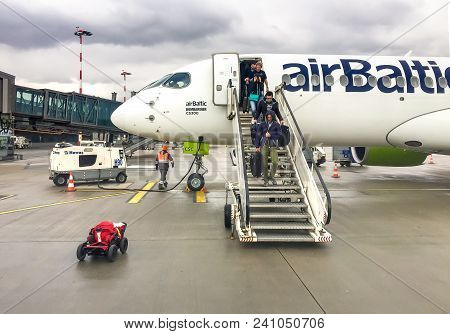 Riga, Latvia - May 5, 2018: Passengers get off the Airbaltic plane arrived in Riga on a rainy day.