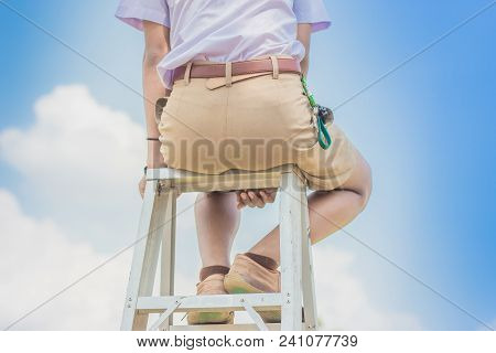 Student Acting Like A Superhero On Top Of Stepladder In School.