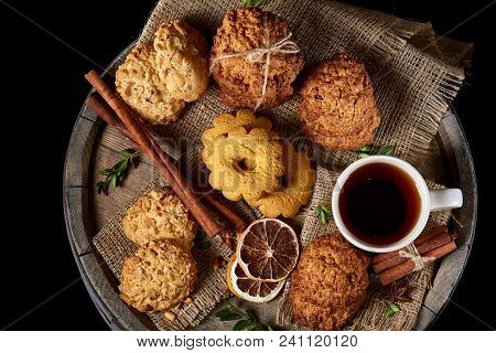Top View Festive Composition With A Cup Of Hot Tea, A Large Set Of Cookies, Cinnamon Sticks Bunch An