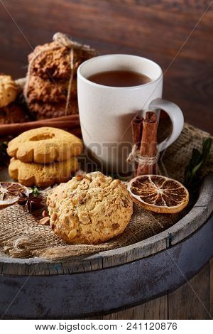 Conceptual Festive Composition With A Cup Of Hot Tea, Large Set Of Cookies, Cinnamon Sticks Bunch An
