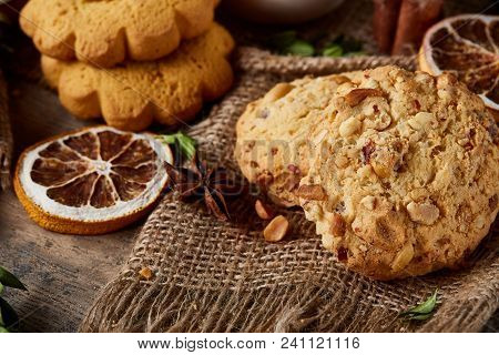 Conceptual Composition With Assortment Of Cookies, Cinnamon Sticks Bunch And Dried Oranges On Burlap