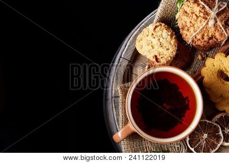Festive Composition With A Mug Of Hot Tea, Assortment Of Cookies, Cinnamon Sticks Bunch And Dried Or
