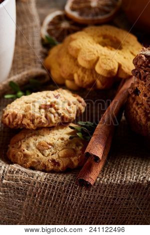 Conceptual Composition With Assortment Of Cookies, Cinnamon Sticks Bunch And Dried Oranges On Burlap