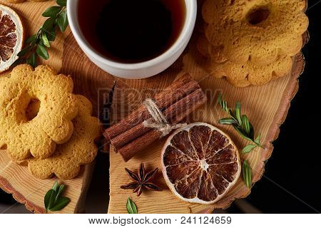 Christmas Concept With A White Porcelain Cup Of Hot Tea, A Large Set Of Cookies, Cinnamon Sticks Bun