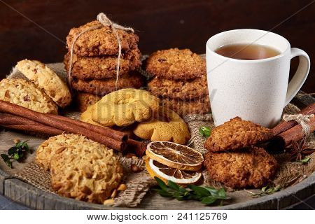Conceptual Festive Composition With A Cup Of Hot Tea, A Large Set Of Cookies, Cinnamon Sticks Bunch 