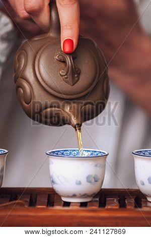 Cropped Shot Of Woman Pouring Tea In Traditional Chinese Teaware.