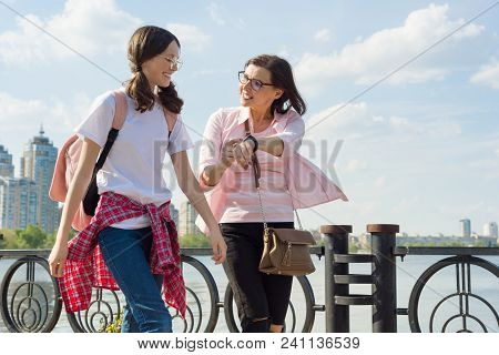 Mother And Daughter Teenager Walk Down The Street, The Woman Looks At The Clock, Rushes, Is Late, Qu