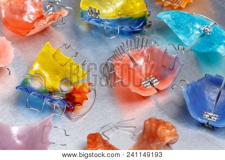 Three Colorful Dental Braces Or Retainers For Teeth On Metall Background, Closeup