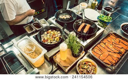 High-angle view of various fresh ingredients on the stove and the counter of a commercial kitchen in a trendy restaurant with fish specialties